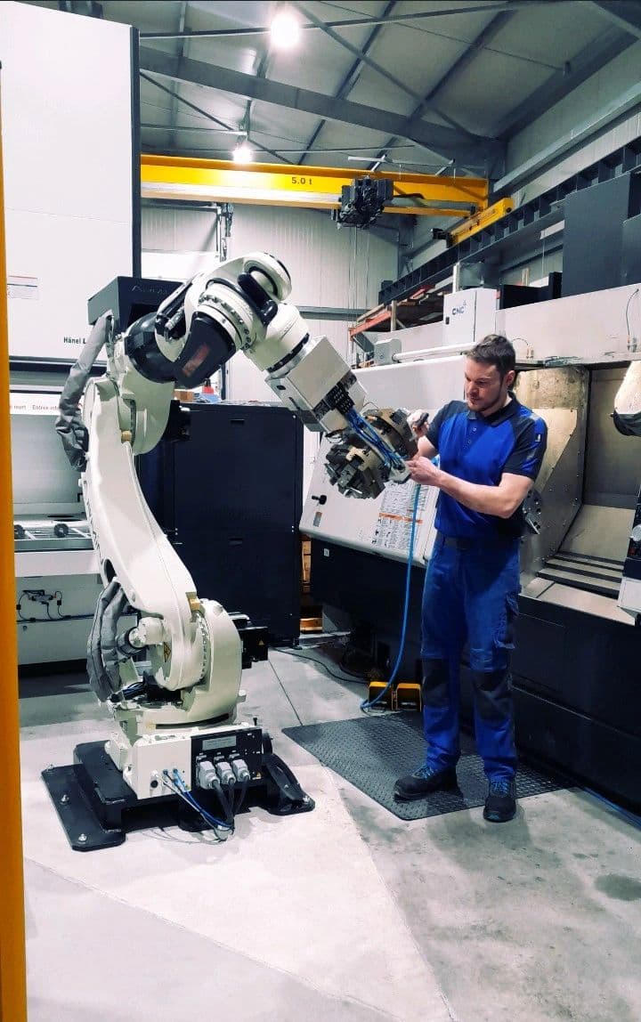 An operator manually changing the gripper jaws — the reality of a part change
