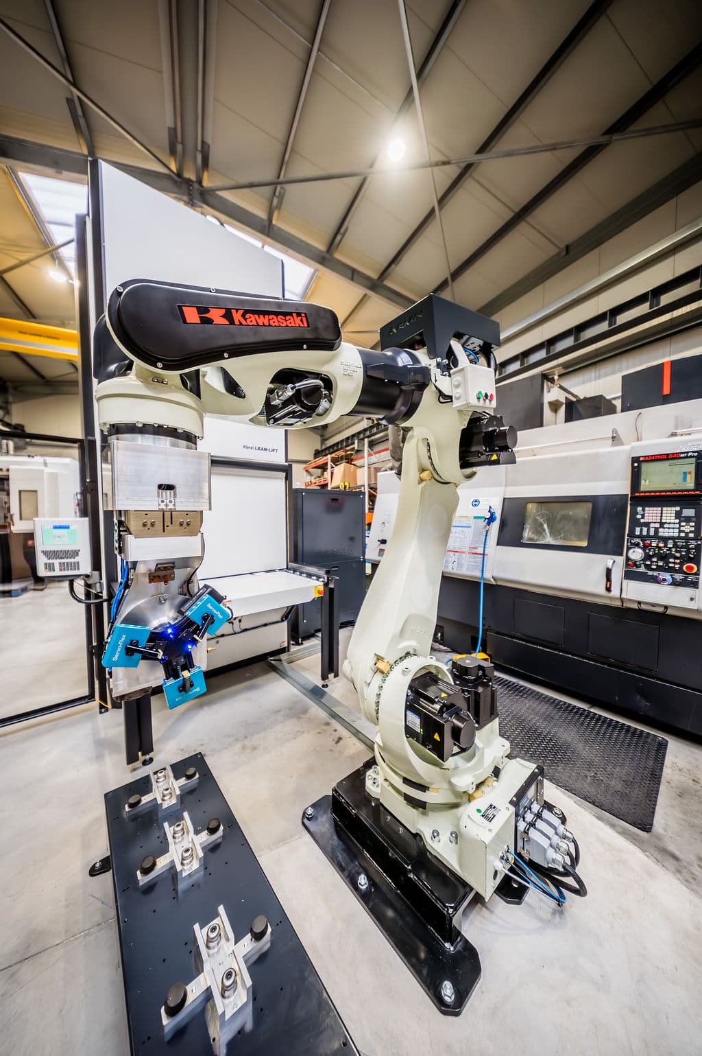 Un robot Kawasaki équipé d'un préhenseur Servo-Flex dans une cellule de production